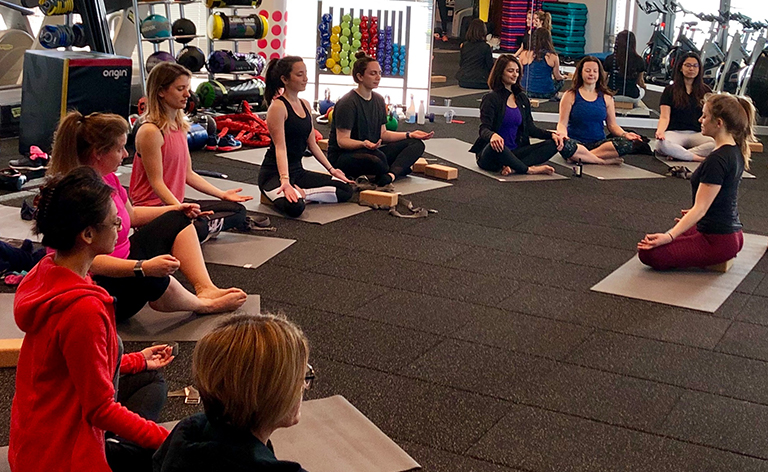 group of people sitting on the ground practicing yoga.