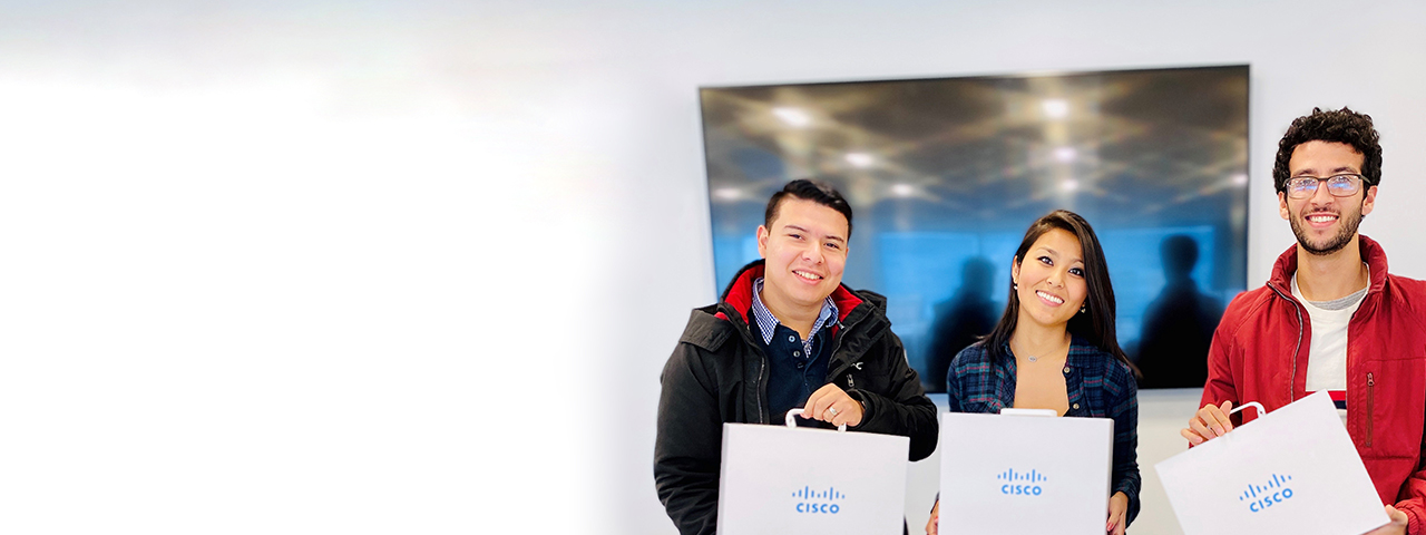 Three people stand together and smile while holding Cisco briefcases.