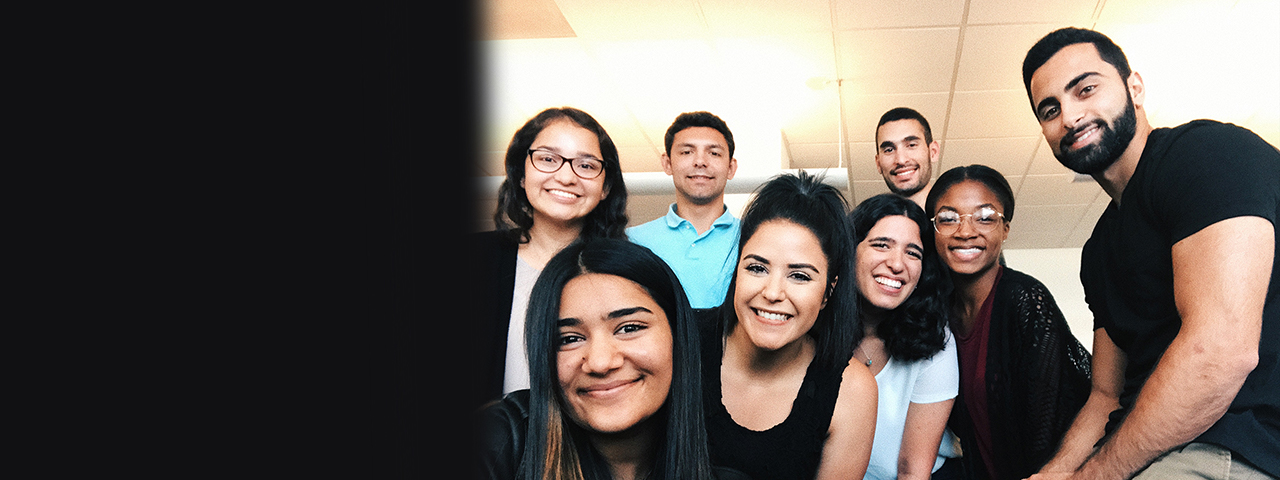 Eight people huddled together and smiling.