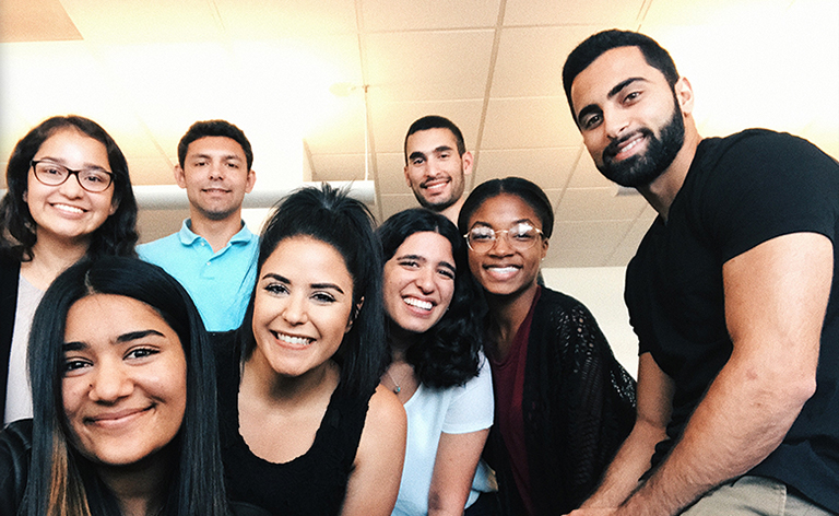 Eight people huddled together and smiling.