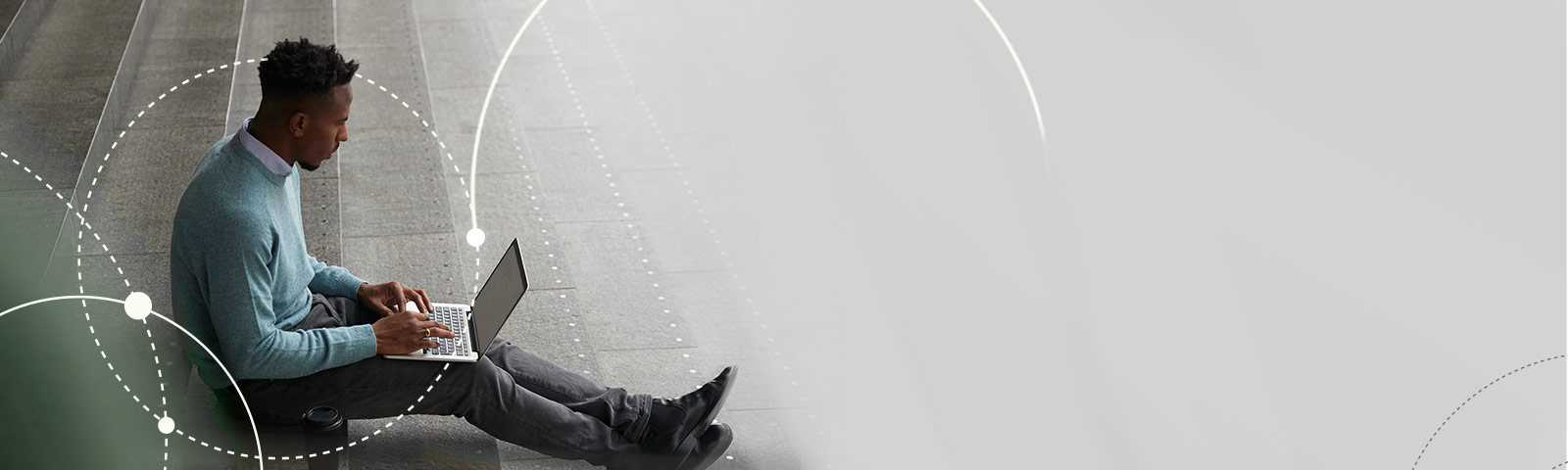 Man sitting on stairs, working on laptop