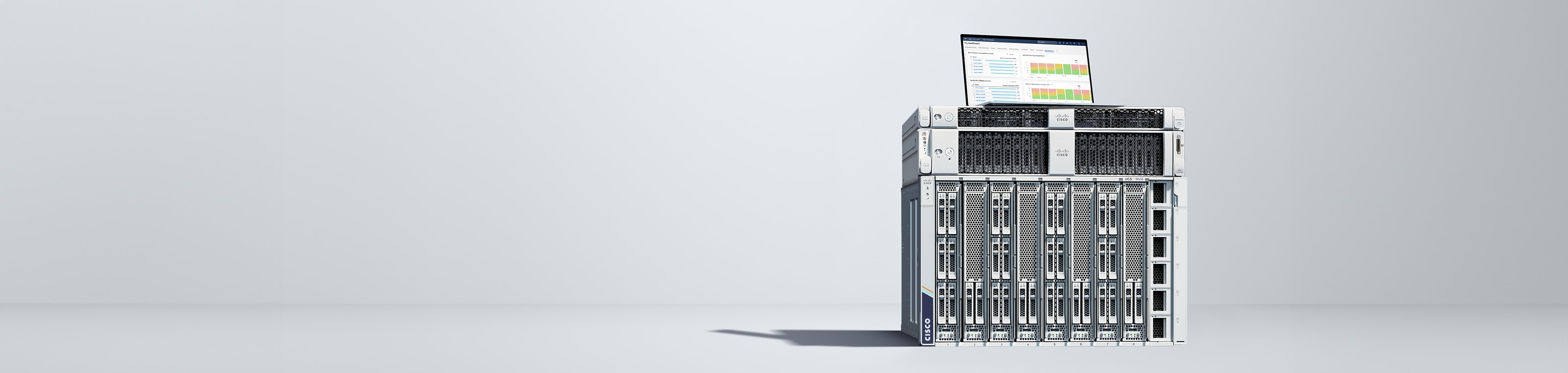 A UCS-X series modular server stacked with a UCS-C220 and a C240 rack server. An open laptop computer is on top of the stack displaying an Intersight dashboard.