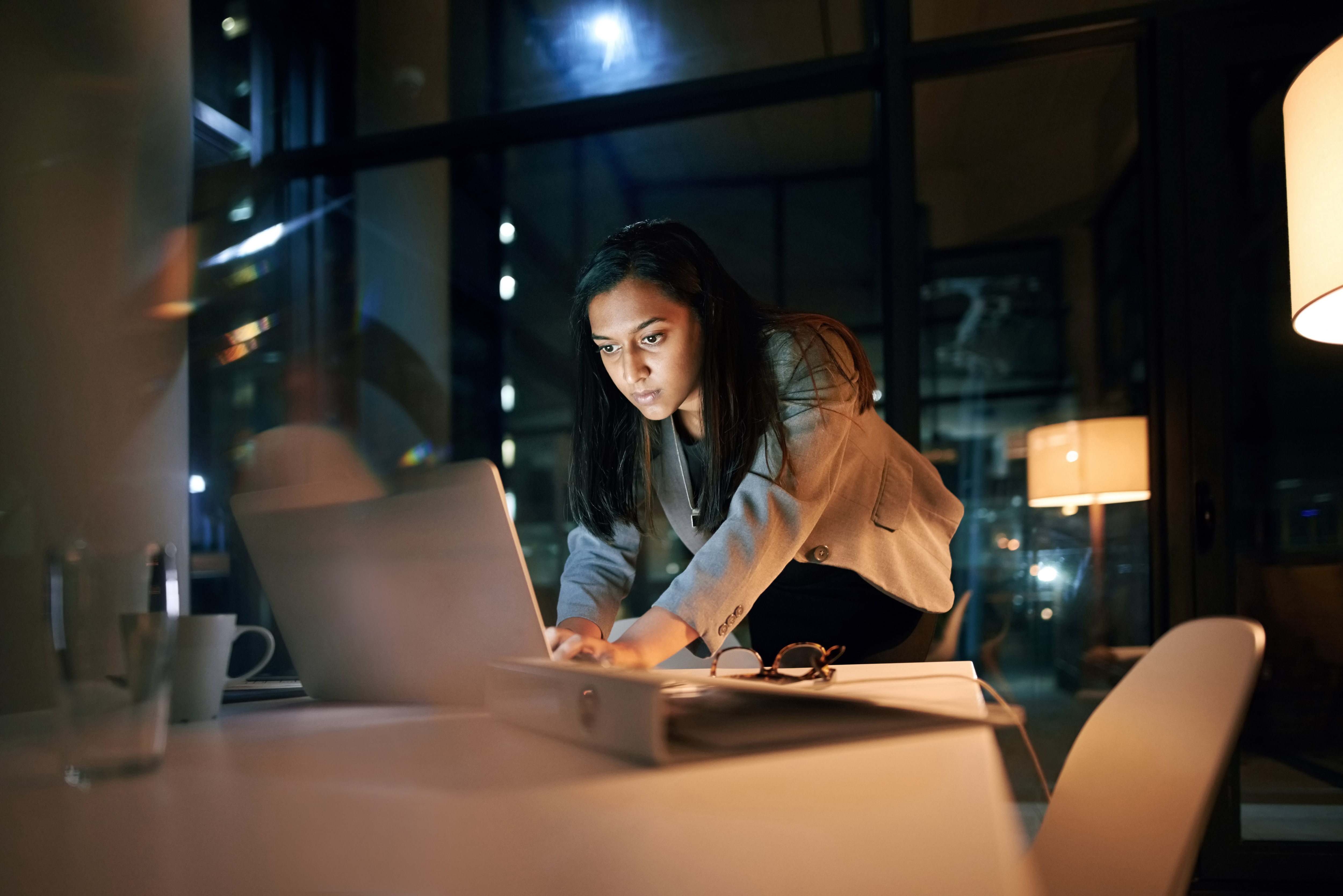 Person typing on a laptop while standing at a conference table